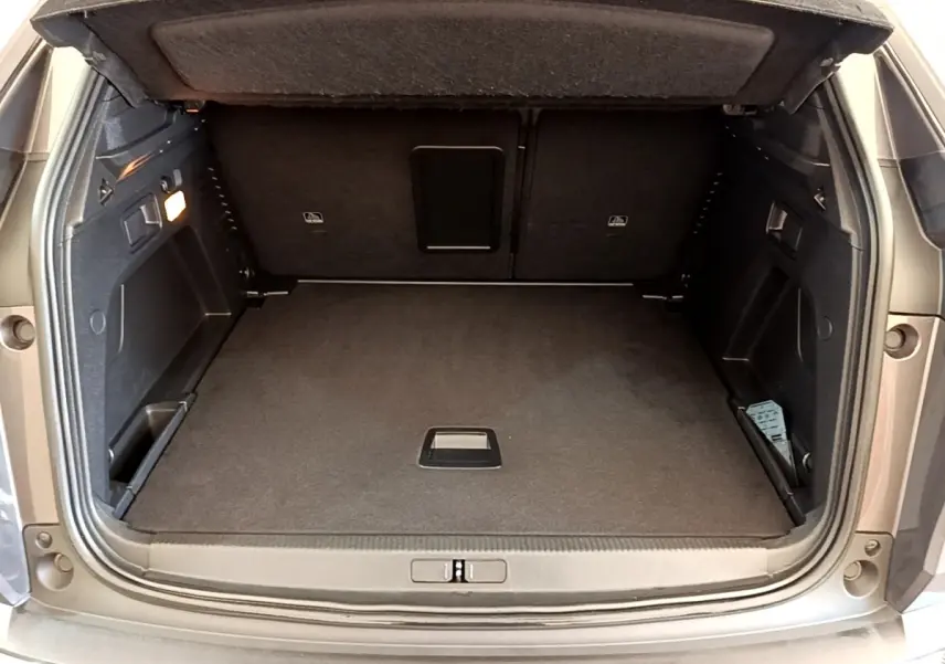 Coffre ouvert vu de l'arrière d'un Peugeot 3008 gris foncé, montrant un espace de chargement propre et spacieux.