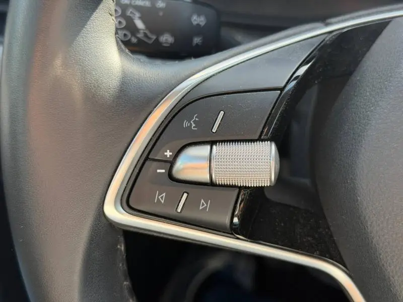 Gros plan sur les commandes de volume et de navigation multimédia au volant du Skoda Kamiq 2025 gris graphite métallisé.