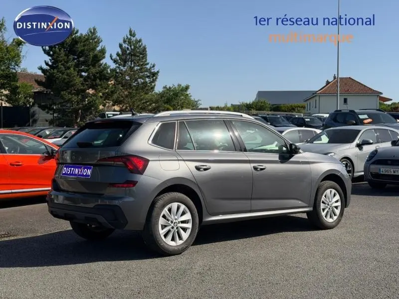 Vue 3/4 arrière droite d'un Skoda Kamiq gris graphite métallisé 2025 avec jantes alliage et toit ouvrant visible.