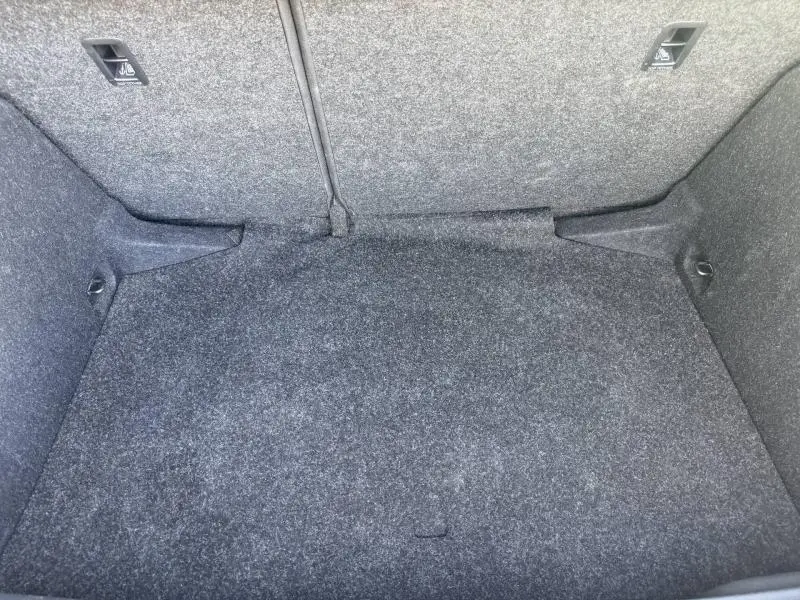 Coffre vide du Skoda Kamiq 2025 en gris graphite, vue intérieure montrant la moquette et les fixations de chargement.