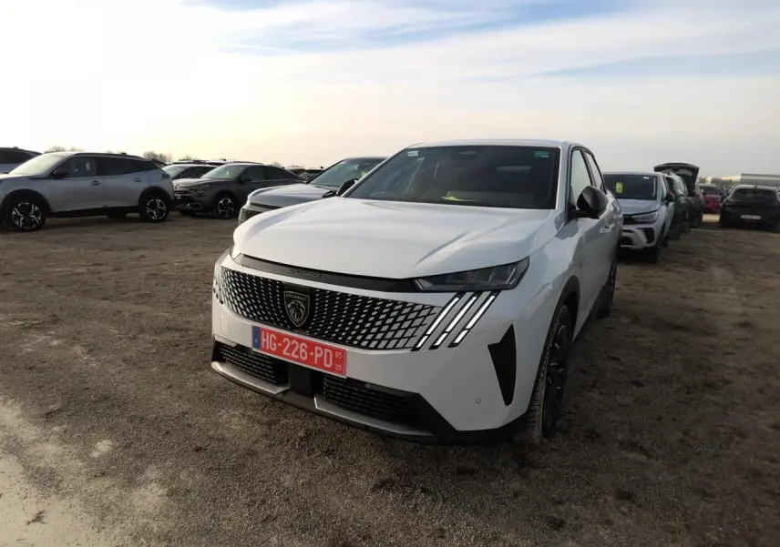 Peugeot 3008 blanc vue 3/4 avant avec calandre à motif géométrique et feux LED griffés, sur parking extérieur.