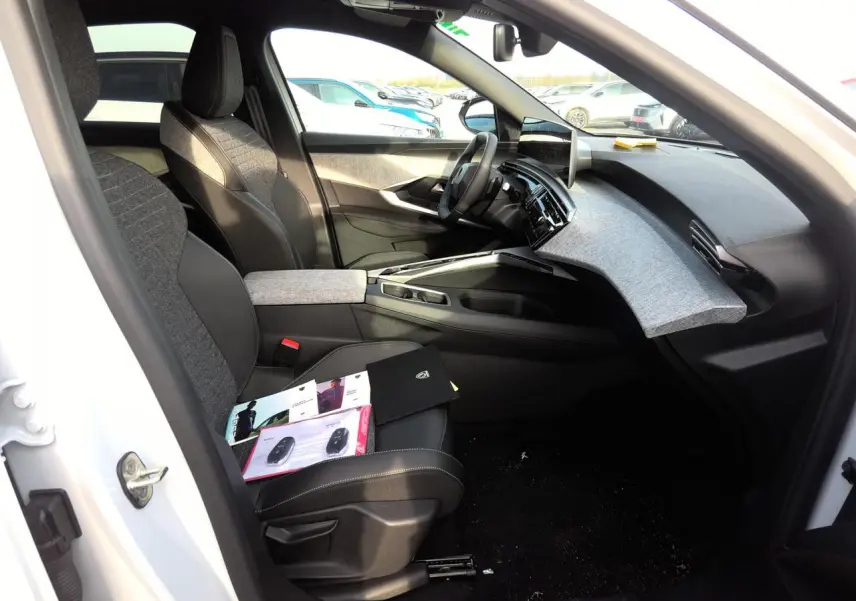 Intérieur avant droit du Peugeot 3008 blanc 2025, avec tableau de bord tissu gris et sièges bi-matière noirs et gris.