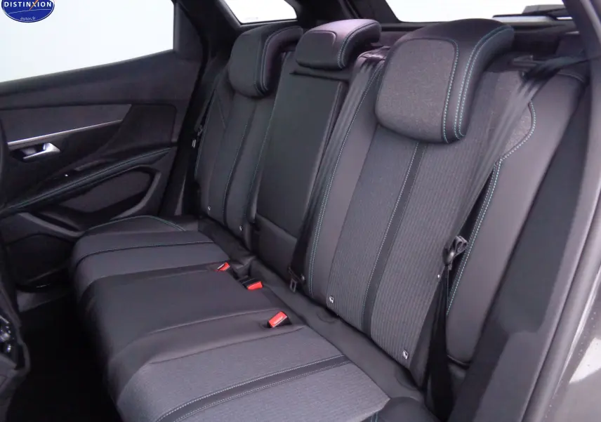 Vue intérieure arrière du Peugeot 3008 2023, sièges noirs avec surpiqûres bleues et ceintures de sécurité visibles.