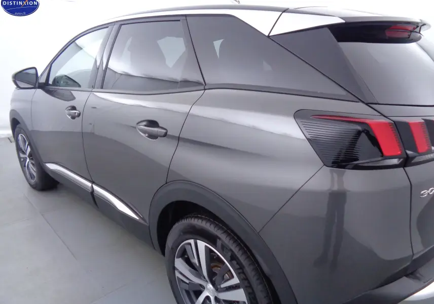 Vue 3/4 arrière gauche d'un Peugeot 3008 gris platinium métallisé avec feux arrière distinctifs et jantes alliage.