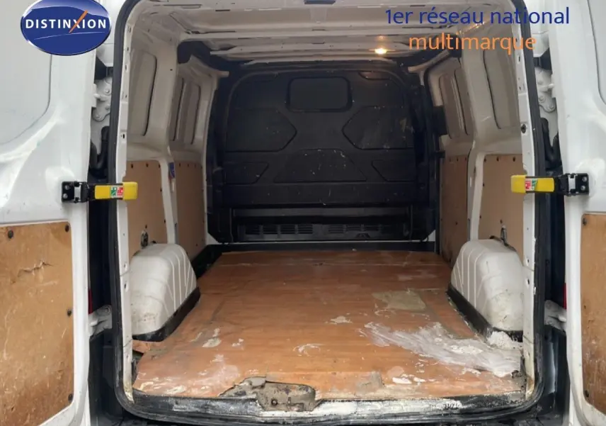Vue arrière intérieure du fourgon Ford Transit Custom blanc, montrant l'espace de chargement avec plancher en bois usé.