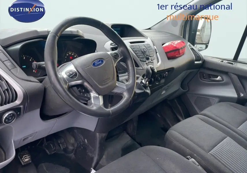 Vue intérieure côté conducteur du Ford Transit Custom blanc de 2016, avec tableau de bord et volant en cuir noir.