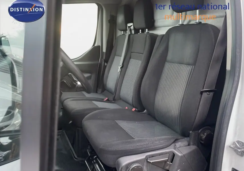 Vue intérieure côté conducteur du Ford Transit Custom blanc 2016, montrant les sièges tissu noir à trois places.
