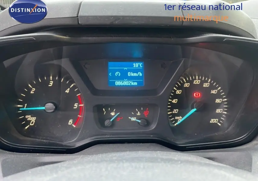 Vue rapprochée du tableau de bord du Ford Transit Custom blanc, affichant 86802 km et vitesse à 0 km/h.