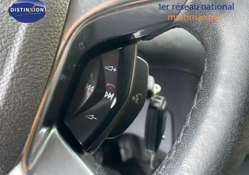 Gros plan sur les commandes au volant d'un Ford Transit Custom blanc, modèle 2016, avec finition noire intérieure.