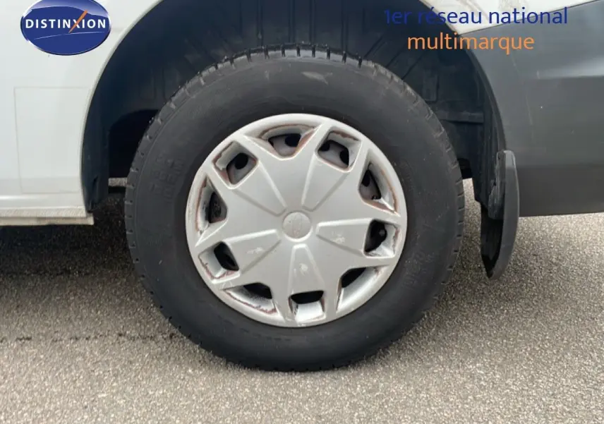 Gros plan sur la roue avant droite d'un Ford Transit Custom blanc de 2016 avec enjoliveur gris usé.