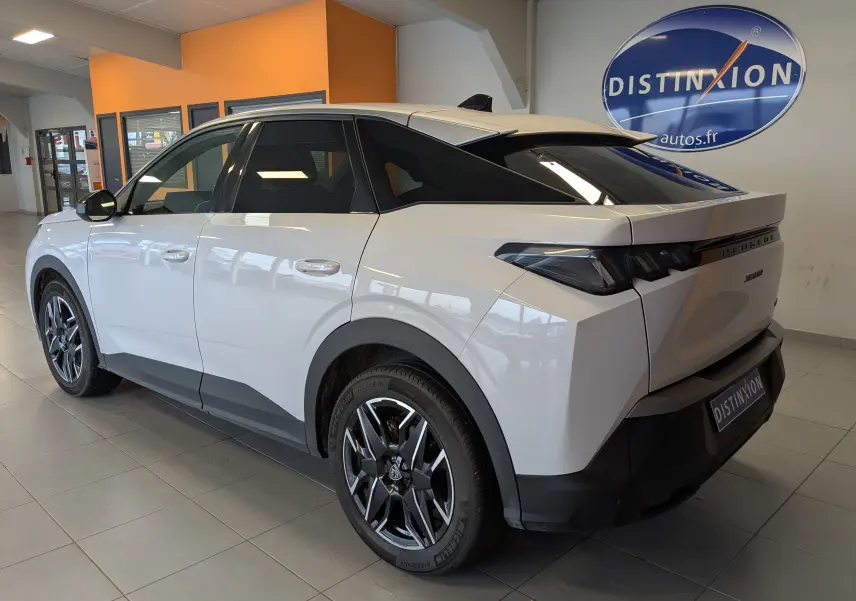 Vue 3/4 arrière droite d’un Peugeot 3008 Hybrid blanc avec jantes aluminium 19’’ et vitres arrière surteintées en showroom.