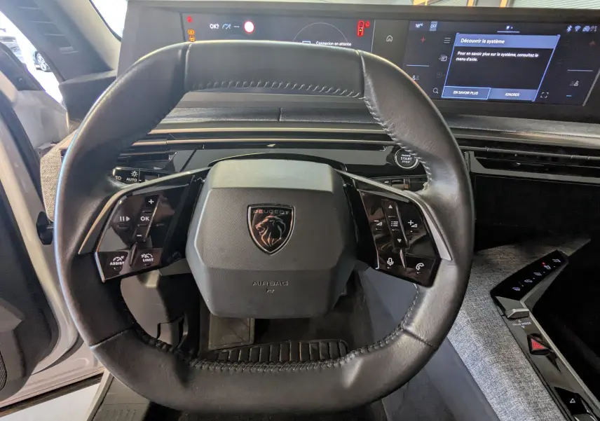 Vue rapprochée du volant cuir noir du Peugeot 3008 Hybrid 145 eDCS6 Allure avec tableau de bord digital et écran tactile.