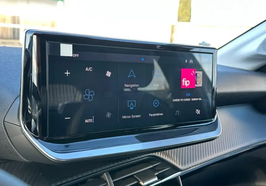 Écran tactile du tableau de bord de la Peugeot 208 Hybrid blanc, vue intérieure côté passager.