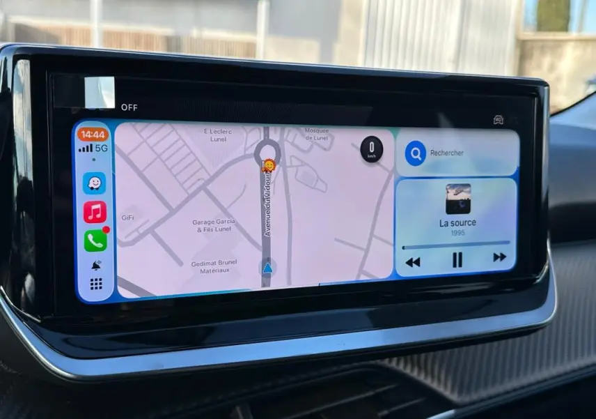 Écran tactile du tableau de bord de la Peugeot 208 Hybrid 110 blanc, affichant navigation et musique.
