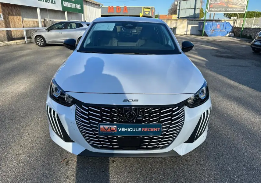 Vue avant d’une Peugeot 208 Hybrid 110 e-DCS6 Allure blanche avec calandre noire et feux LED distinctifs.