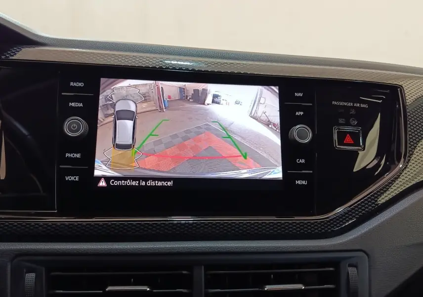 Écran tactile central du Volkswagen Taigo 2023 affichant l'aide au stationnement arrière avec guidage visuel couleur.