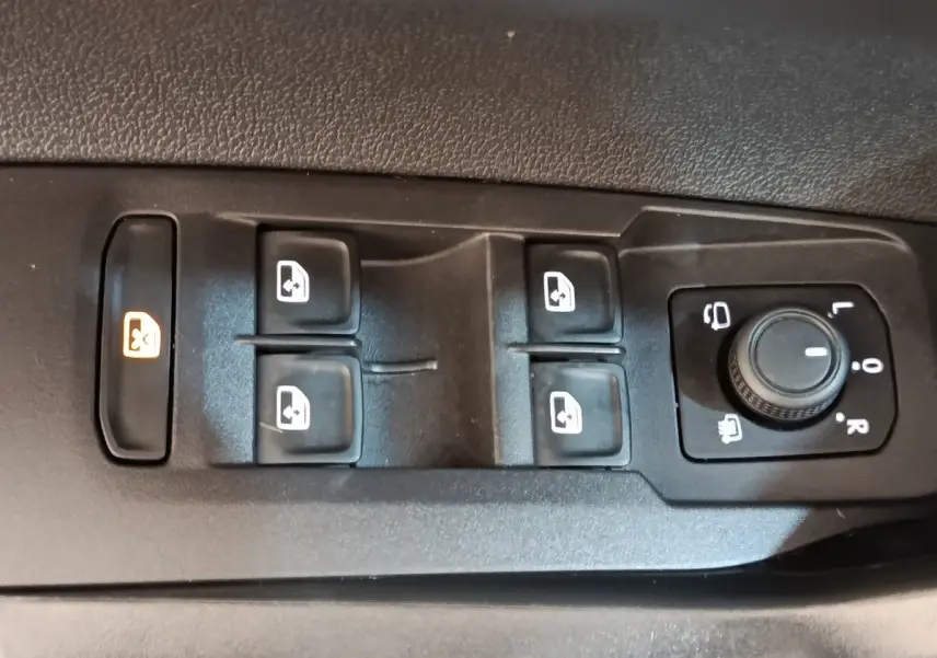 Gros plan sur les commandes des vitres et rétroviseurs côté gauche d’un Volkswagen Taigo gris foncé 2023.