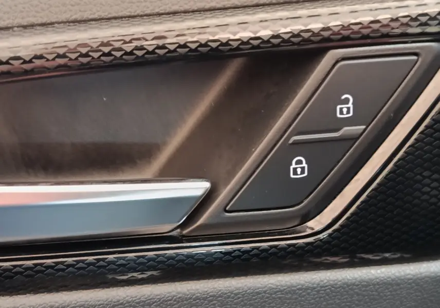 Gros plan sur la poignée intérieure et les boutons de verrouillage de porte du Volkswagen Taigo gris foncé 2023.