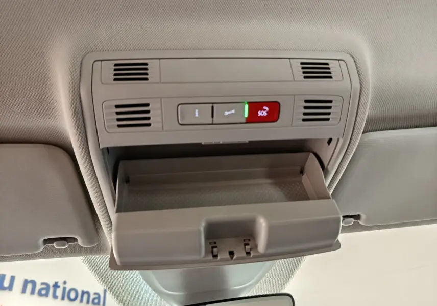 Vue intérieure du plafond avant du Volkswagen Taigo 2023, avec rangement ouvert et boutons SOS visibles en gris clair.