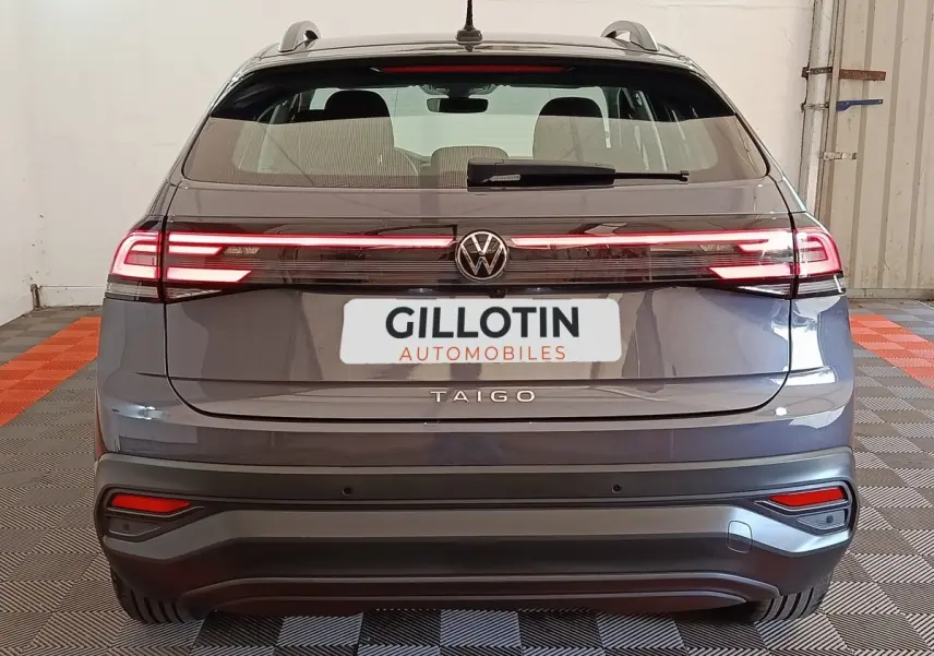 Vue arrière d'un Volkswagen Taigo gris foncé 2023 avec feux arrière LED allumés et logo central visible.