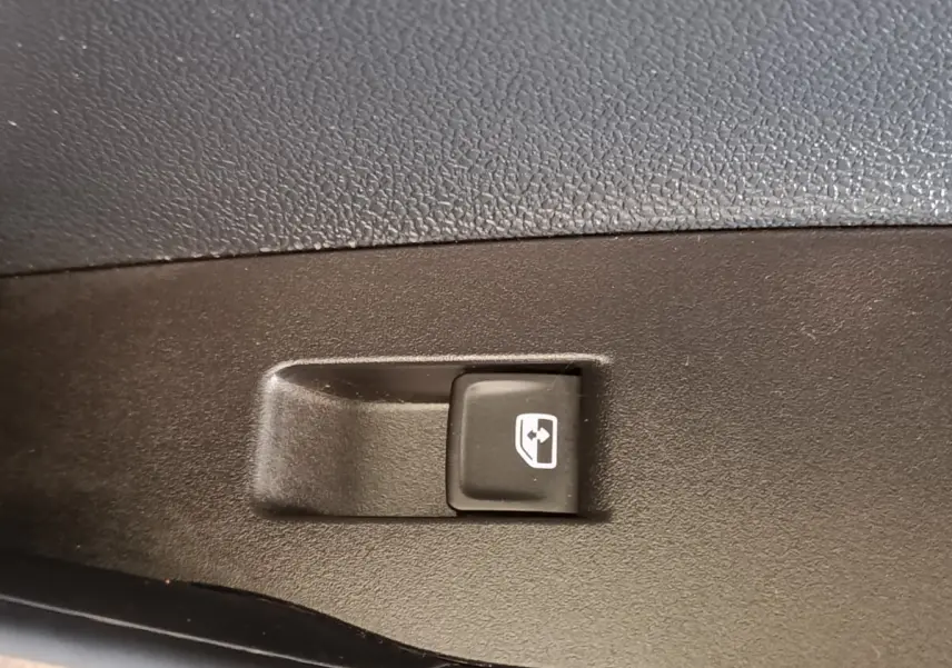 Bouton de commande de lève-vitre électrique sur panneau de porte intérieur noir du Volkswagen Taigo gris foncé.