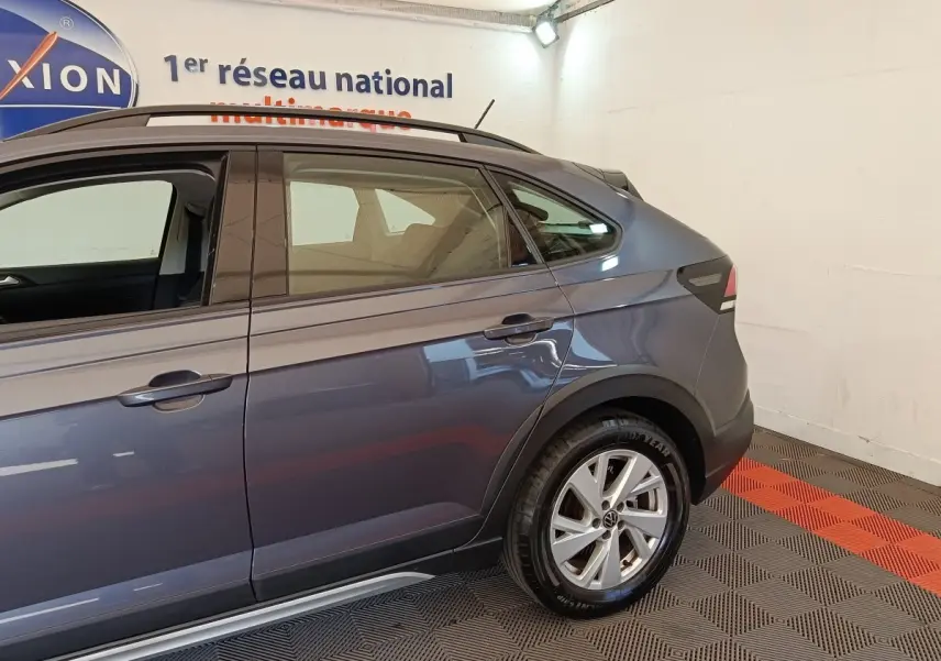 Vue latérale droite du Volkswagen Taigo gris foncé 2023, mettant en valeur la porte arrière et la roue arrière.