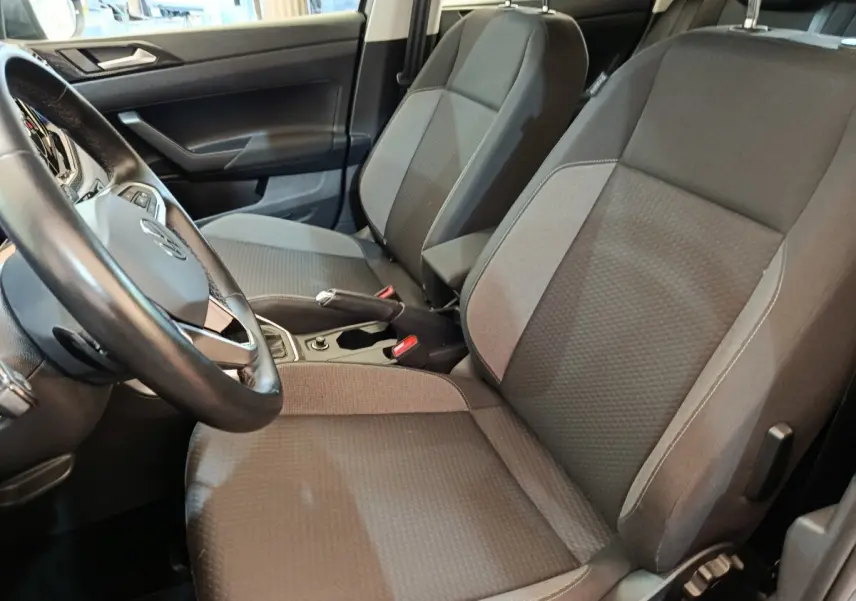 Vue intérieure côté conducteur du Volkswagen Taigo 2023, sièges tissu gris foncé avec volant et console centrale visibles.