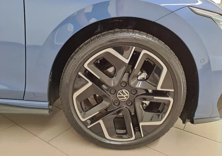 Gros plan sur la roue avant droite d'une Volkswagen Golf Bleu Anémone avec jante alliage R-Line au design moderne.