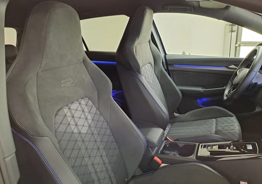 Vue intérieure côté droit de la Volkswagen Golf 1.5 eTSI R-Line 2025 avec sièges sport noirs et éclairage d'ambiance bleu.