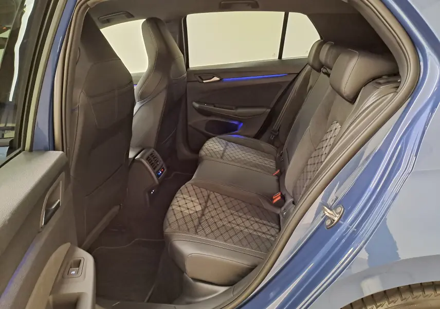 Vue intérieure arrière côté gauche de la Volkswagen Golf 1.5 eTSI 150 DSG7 R-Line Edition bleu Anémone avec sièges en tissu et cuir noir.