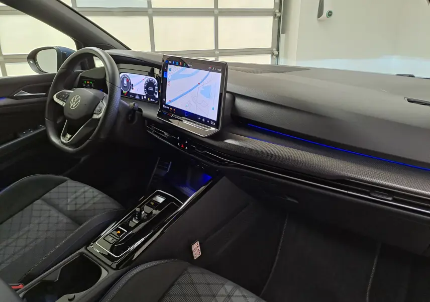 Vue intérieure côté conducteur de la Volkswagen Golf 1.5 eTSI R-Line 2025 avec écran tactile et éclairage d'ambiance bleu.