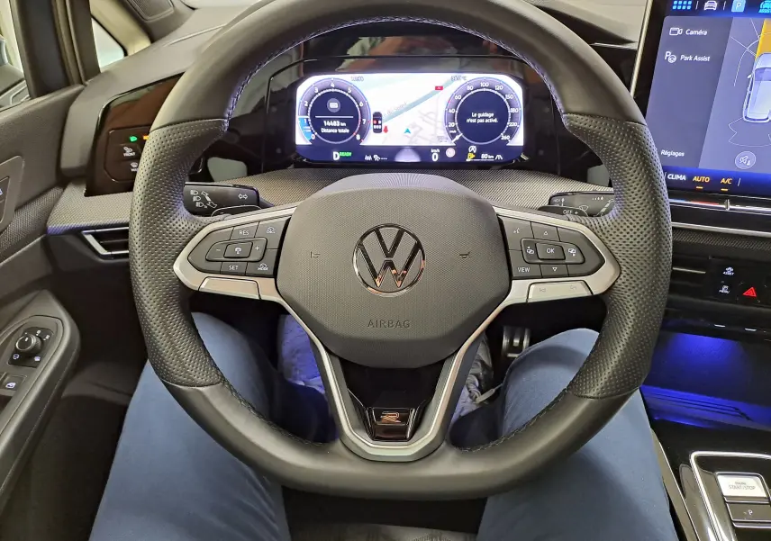 Vue intérieure centrée sur le volant multifonction de la Volkswagen Golf 1.5 eTSI R-Line avec tableau de bord digital et écran tactile.