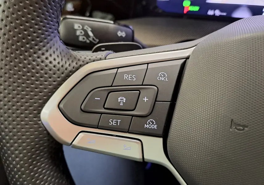 Gros plan sur les commandes du régulateur de vitesse au volant perforé d'une Volkswagen Golf 1.5 eTSI 2025.
