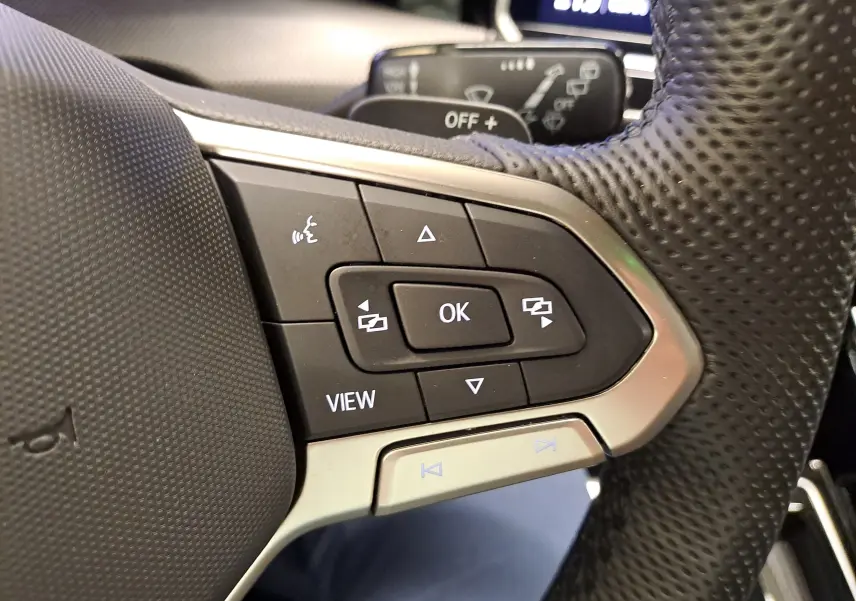 Gros plan sur les commandes multifonctions au volant perforé d'une Volkswagen Golf 1.5 eTSI Bleu Anémone, version R-Line.