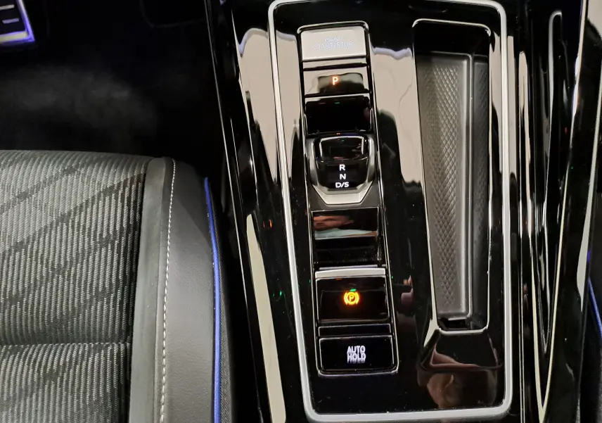 Gros plan sur la console centrale noire brillante de la Volkswagen Golf 1.5 eTSI 150 DSG7 R-Line, avec commandes de boîte auto.