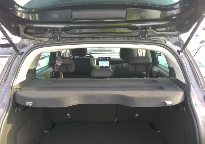 Vue arrière ouverte du coffre d'une Citroën C3 Aircross noire avec tablette cache-bagages et sièges arrière visibles.