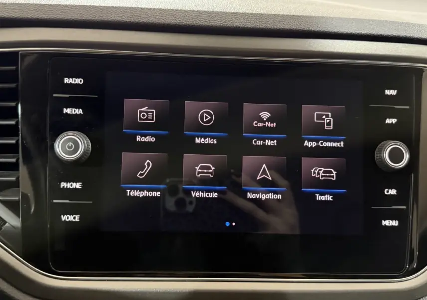 Écran tactile central du tableau de bord du Volkswagen T-Roc blanc, affichant les options multimédia et navigation.