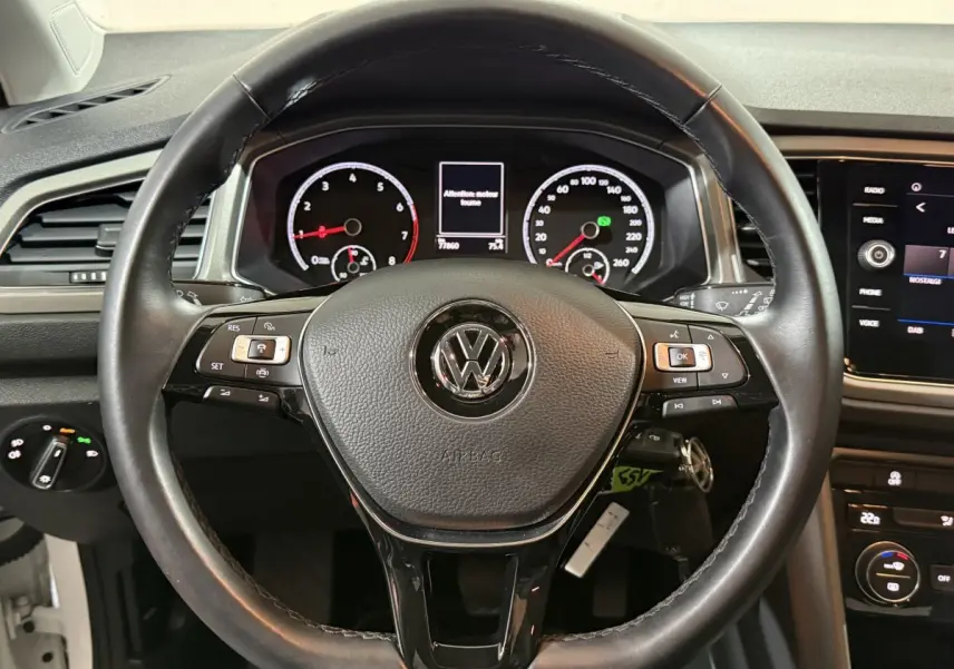 Vue rapprochée du volant cuir noir du Volkswagen T-Roc 2020 avec tableau de bord et écran tactile visibles.