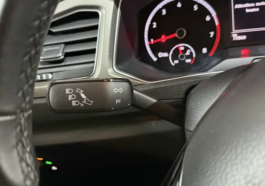 Gros plan sur le commodo gauche et le tableau de bord numérique du Volkswagen T-Roc blanc 2020, intérieur noir.