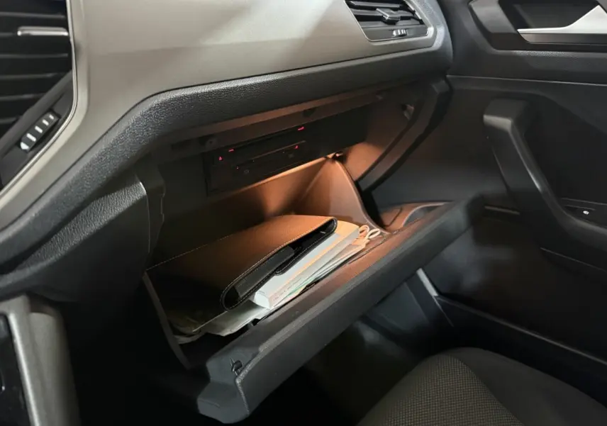 Gant de boîte à gants ouvert côté passager dans un Volkswagen T-Roc blanc, intérieur noir avec éclairage doux.