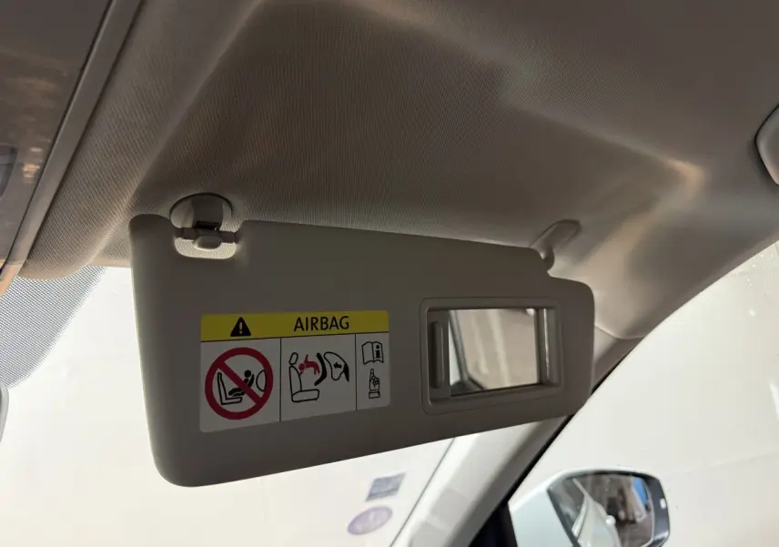 Pare-soleil côté conducteur beige avec miroir intégré et avertissement airbag dans un Volkswagen T-Roc blanc 2020.