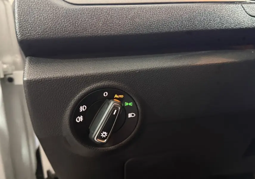 Gros plan sur la commande des phares du Volkswagen T-Roc blanc 2020, avec réglage automatique activé.