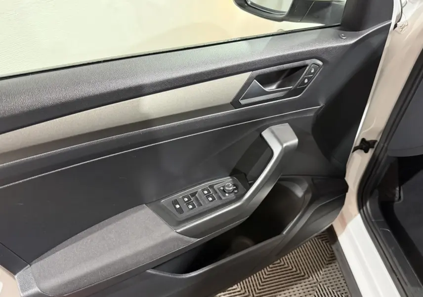 Vue intérieure de la porte côté conducteur du Volkswagen T-Roc blanc, avec commandes électriques des vitres et verrouillage.