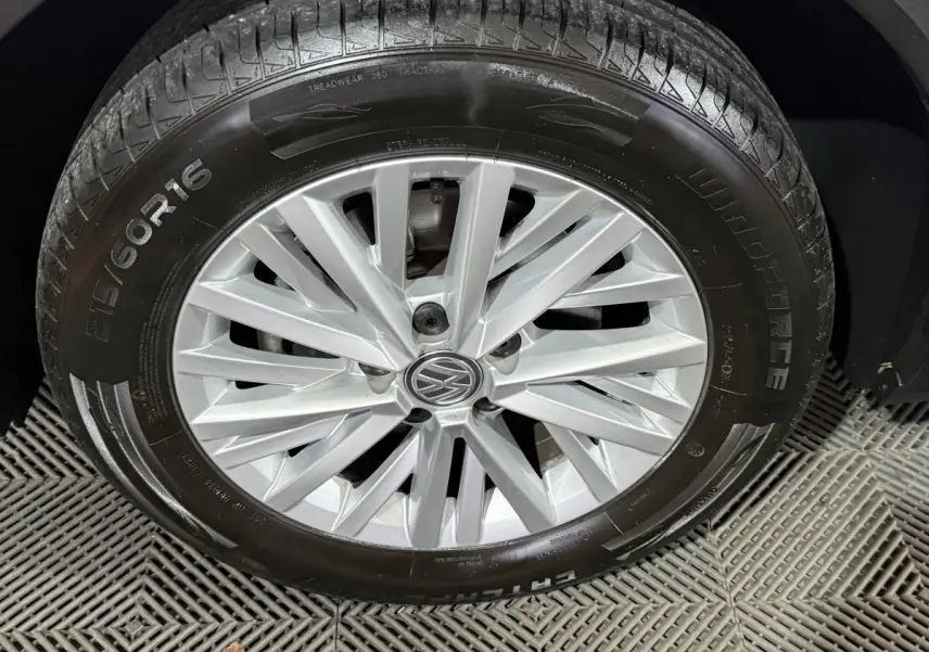 Gros plan sur la roue avant droite du Volkswagen T-Roc blanc avec jante alliage argentée et logo VW central.