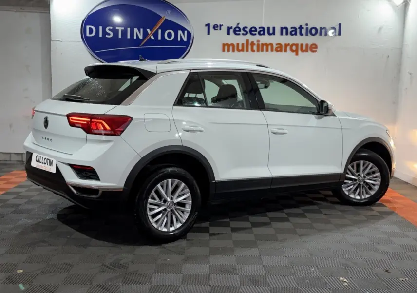 Vue 3/4 arrière droite d'un Volkswagen T-Roc blanc 2020 en intérieur avec jantes alliage et feux LED allumés.