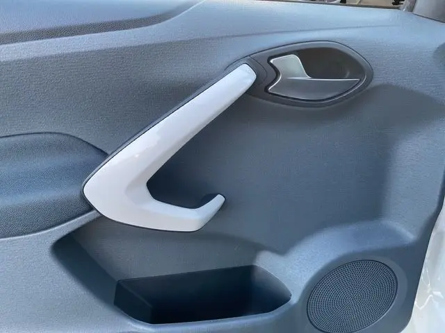 Poignée de porte intérieure blanche côté gauche d'une Ford KA 1.2 69 TREND 2015 avec panneau noir et haut-parleur intégré.