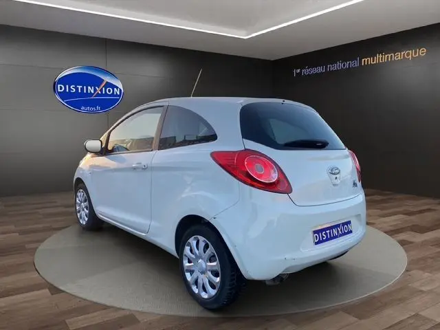 Vue 3/4 arrière droite d'une Ford KA blanche de 2015, compacte avec feux arrière ronds et jantes argentées.