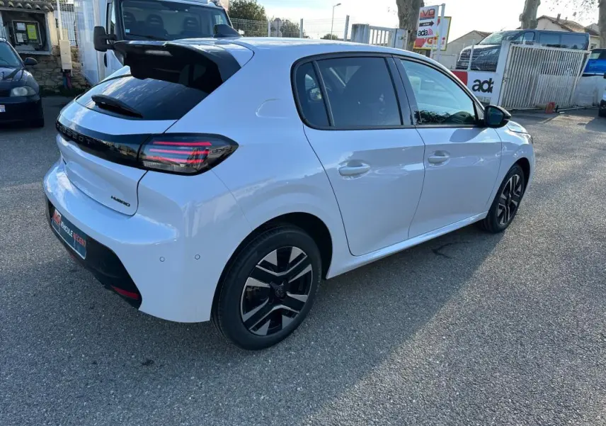 Vue 3/4 arrière droite d'une Peugeot 208 Hybrid 110 blanche avec jantes alliage noires et feux arrière LED distinctifs.