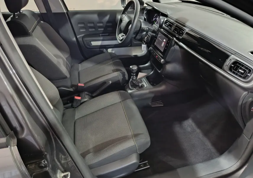 Vue intérieure côté conducteur de la Citroën C3 2024 gris foncé, avec tableau de bord tactile et volant multifonctions.
