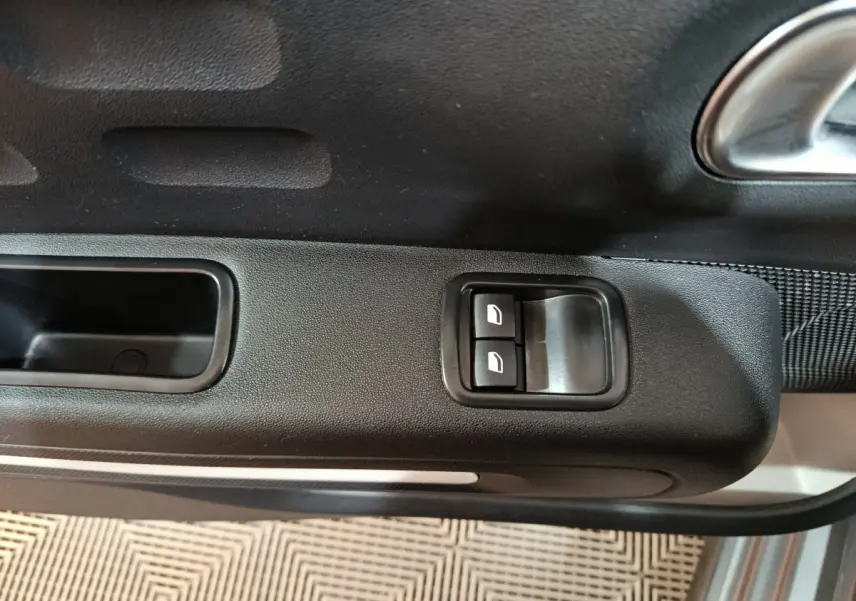 Gros plan sur les commandes des vitres électriques sur la porte côté conducteur d'une Citroën C3 gris foncé 2024.